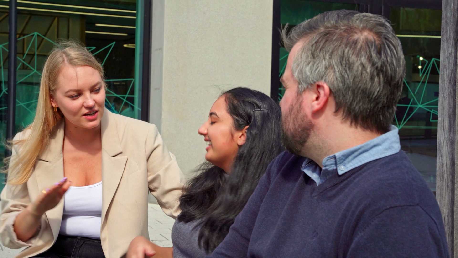 Three people outside, engaged in conversation.